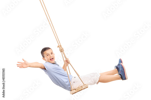 Joyful little boy swinging on a swing
