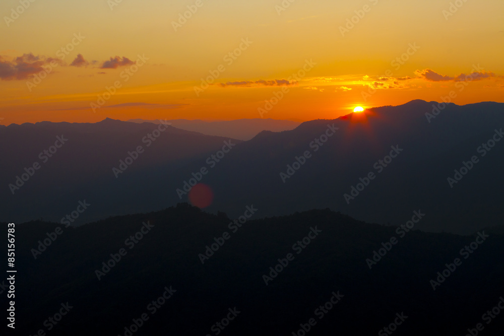 Naklejka premium dramatic sky sun set over mountain with orange dramatic sky with lensflare