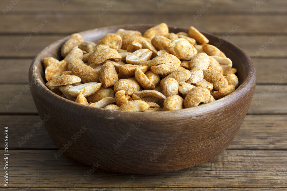 Spicy dry roasted peanuts in rustic wood bowl. Spicy dry roasted peanuts in rustic wood bowl.