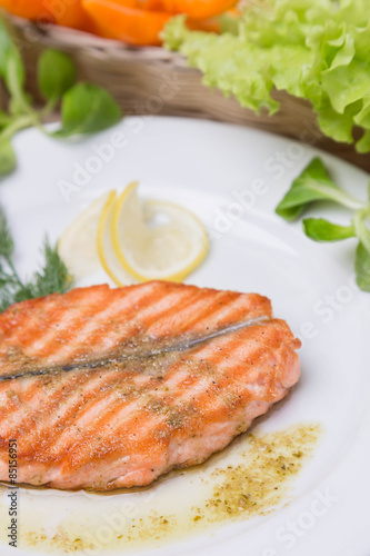 hot grilled salmon with garnish on white plate