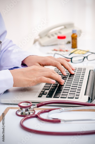 close up of doctor typing information on the computer in office