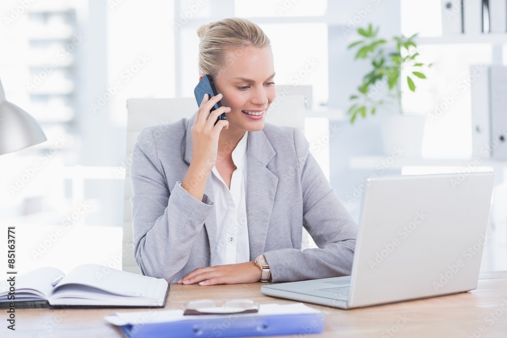 Smiling businesswoman looking at camera with her phone 