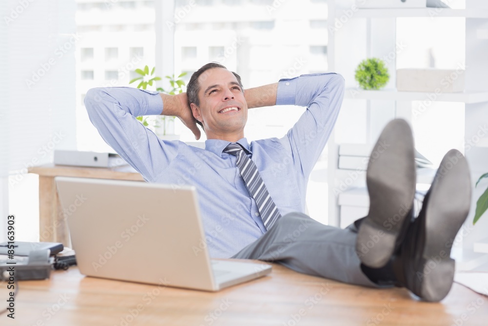 Smiling businessman relaxing on his office Smiling businessman relaxing on his office
