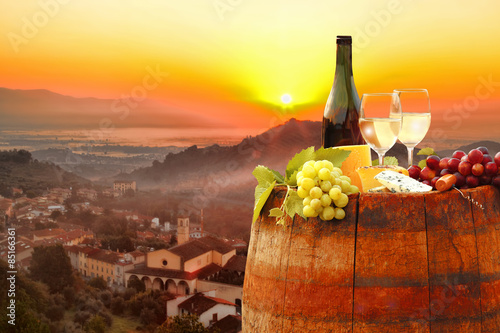 White wine with barrel against colorful sunset in Chianti, Tuscany, Italy