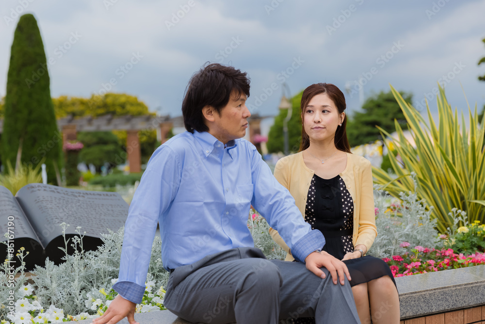 Naklejka premium 公園のベンチで話すカップル