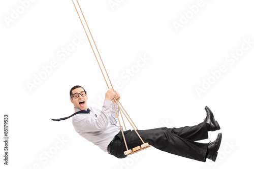 Delighted young man swinging on a swing