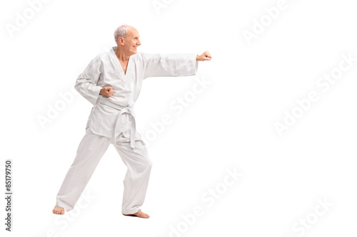 Old man in a white kimono practicing karate