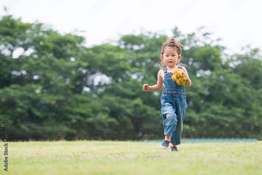 オーバーオールを着てテディーベアーで遊ぶ女の子