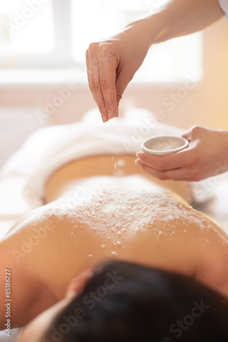 Spa Woman. Brunette Getting a Salt Scrub Beauty Treatment in Salon