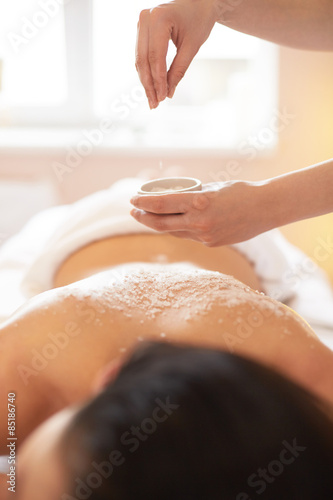 Spa Woman. Brunette Getting a Salt Scrub Beauty Treatment in Salon