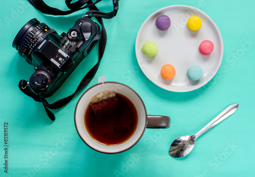 colorful french macaron,cup of tea and SLR camera on green background-Top view