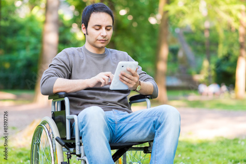 Disabled man using a tablet in a park