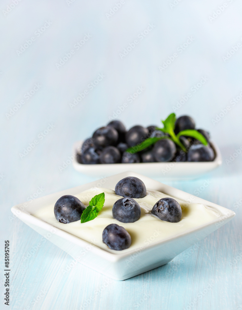 Yogurt with ripe blueberries on a wooden background. Yogurt with ripe blueberries on a wooden background.