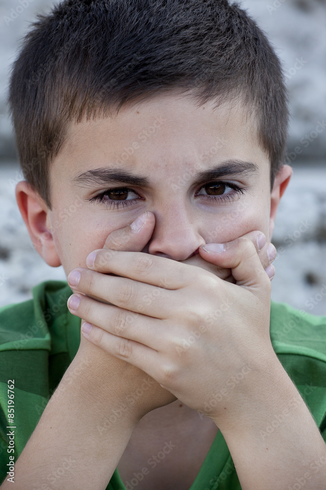 Portrait of a child covering his mouth with his hands Portrait of a child covering his mouth with his hands