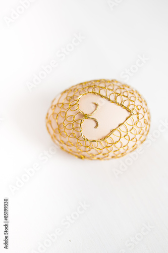 A beautiful easter egg covered in golden net with a heart shape