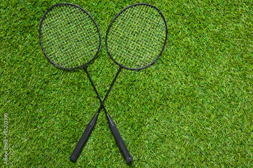 Two badminton rackets lying crossed on the grass