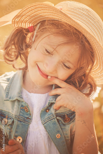 cute happy child girl in straw portrait on summer field photo