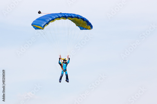 Parachutist in a blue suit on blue yellow parachute