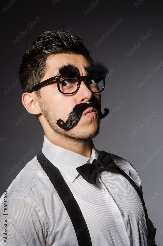 Obraz premium Young man with false moustache isolated on gray