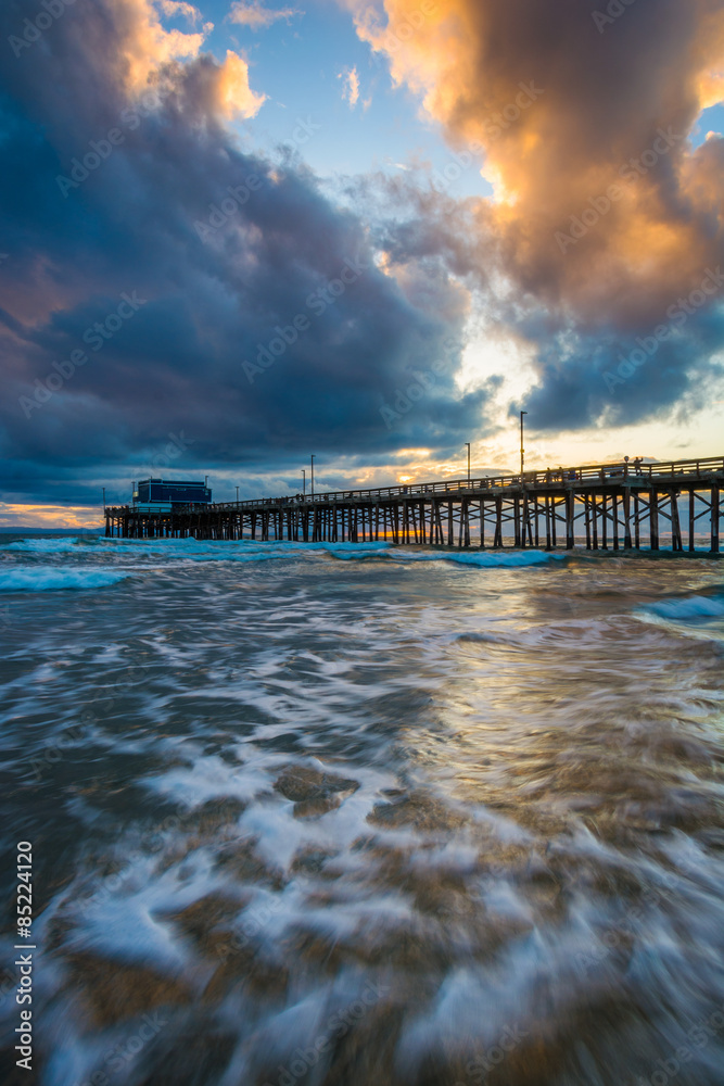 Waves in the Pacific Ocean and the Newport Pier at sunset, in Ne