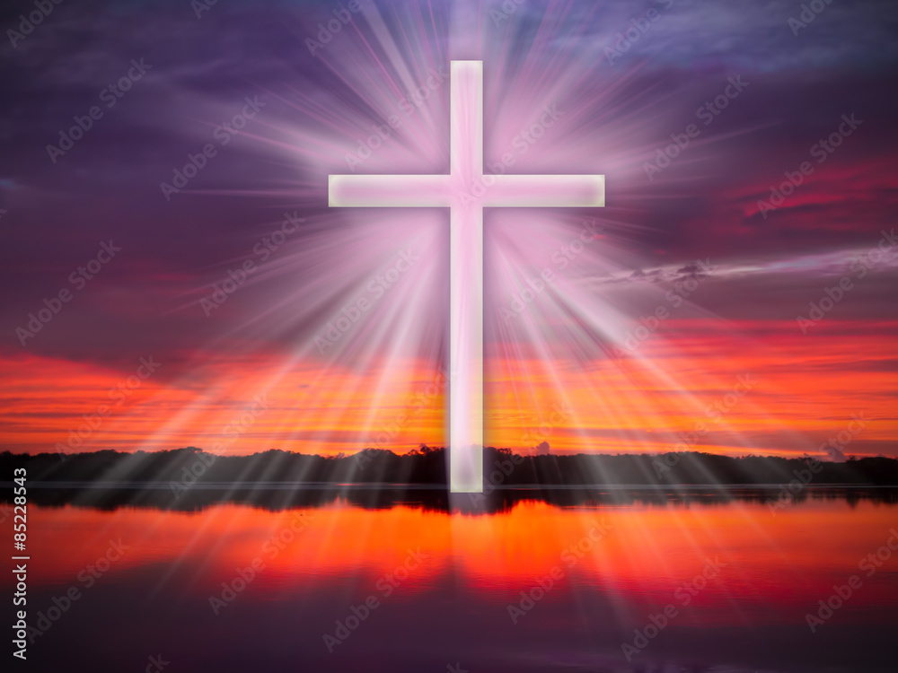 A cross in the sky over a river or coean with light rays at sunrise or sunset.