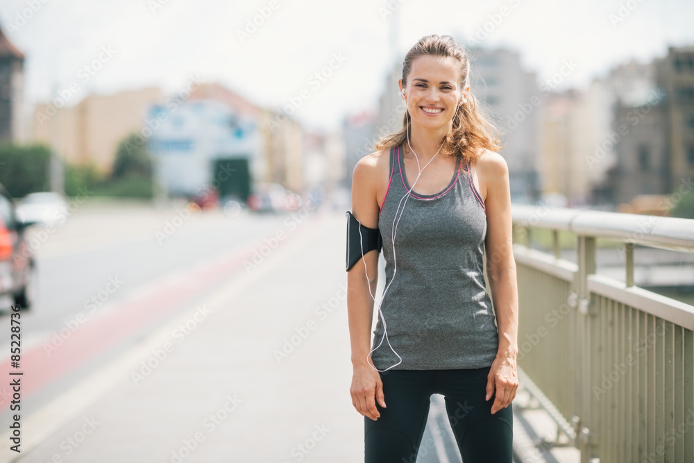 Smiling woman jogger standing still on bridge Smiling woman jogger standing still on bridge