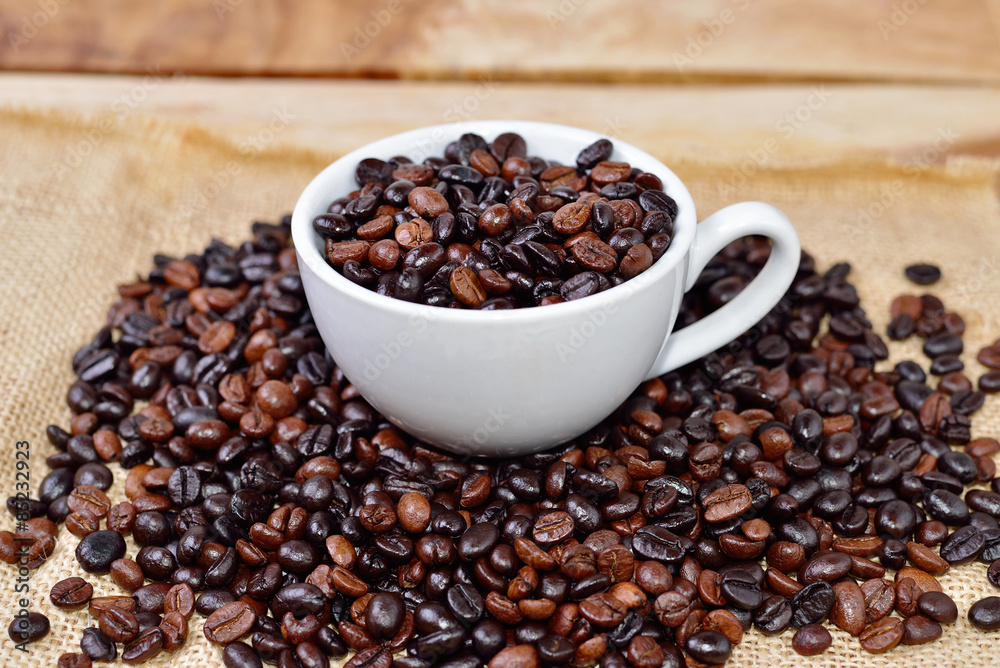 Cup full of coffee beans on the cloth sack Cup full of coffee beans on the cloth sack