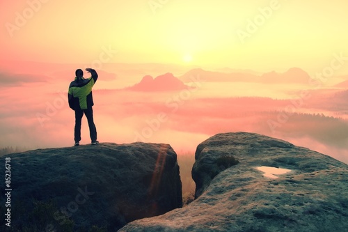 Moment of loneliness. Man on the rock empires and watch over the misty and foggy morning valley to Sun