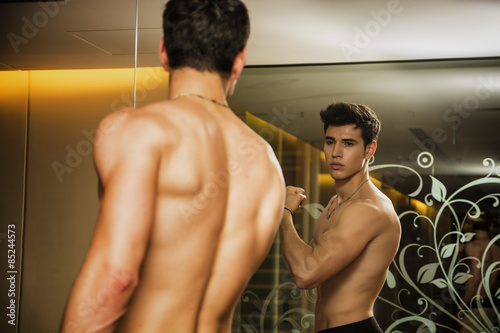 Young Man Admiring Bicep Muscles in Mirror