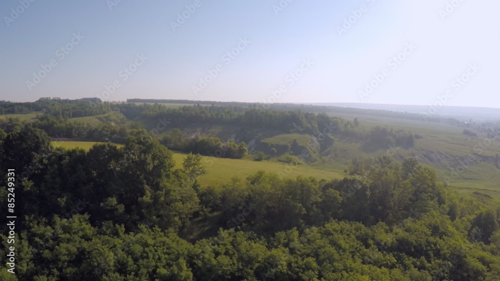 bird's-eye view forest, farmland, ravine dawn sun rays