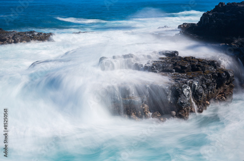 Raging sea flows over lave rocks on shore line