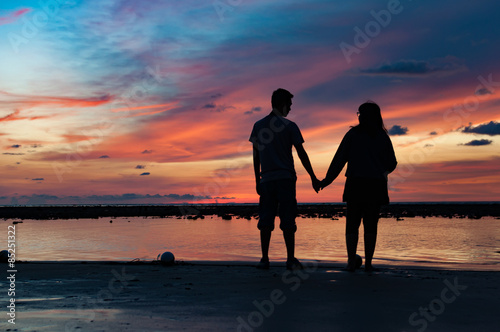 Silhouette of couple hold each other hand at the beach