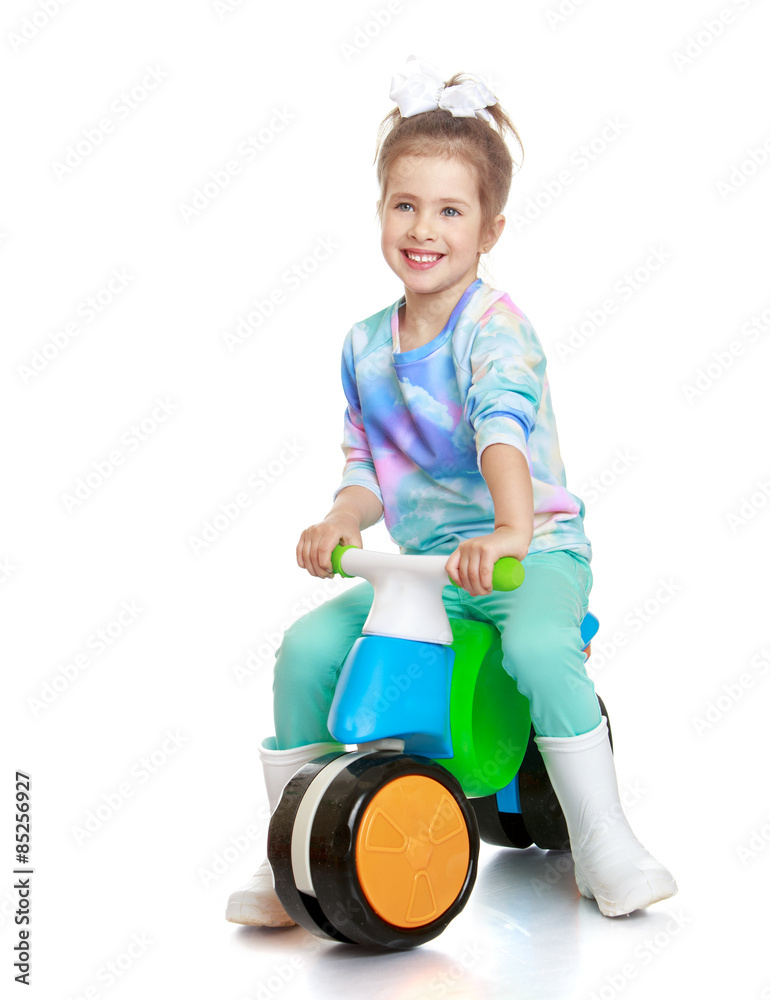 Little girl in rubber boots is riding on a little bike Little girl in rubber boots is riding on a little bike