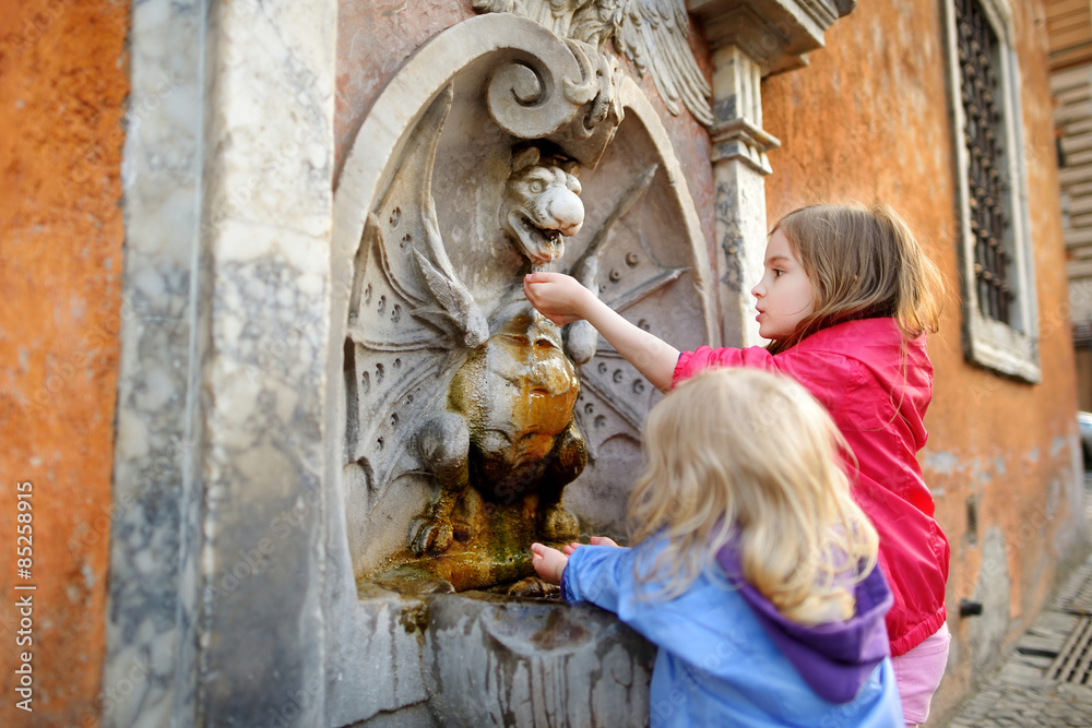 Two girls playing with drinking water fountain