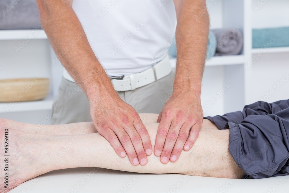 Physiotherapist doing leg massage to his patient 