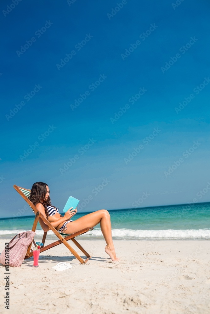 Pretty brunette reading a book on deck chair Pretty brunette reading a book on deck chair