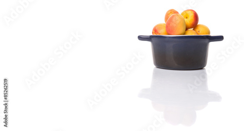 Fototapeta Naklejka Na Ścianę i Meble -  Ripe apricot fruits in a bliue pot over white background