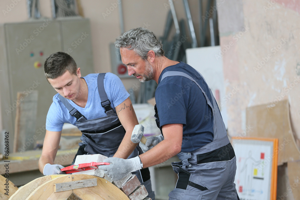 Teenager with professional brick layer in training school Teenager with professional brick layer in training school