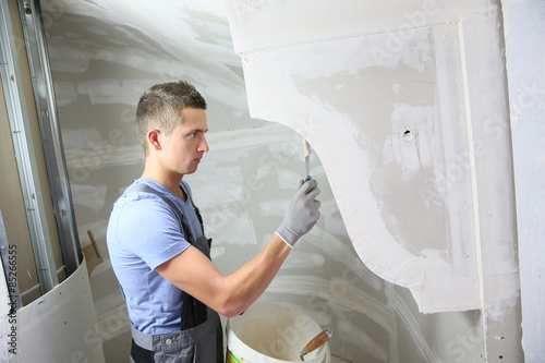 Young plasterer working on indoor wall photo