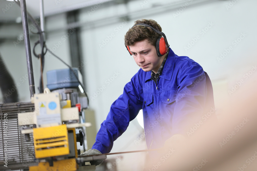 Young man in metallurgy workshop working on machine Young man in metallurgy workshop working on machine
