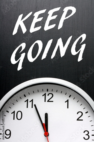 The phrase Keep Going on a blackboard next to a clock