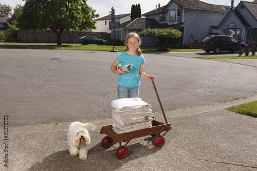Young girl delivering newspapers with her dog.