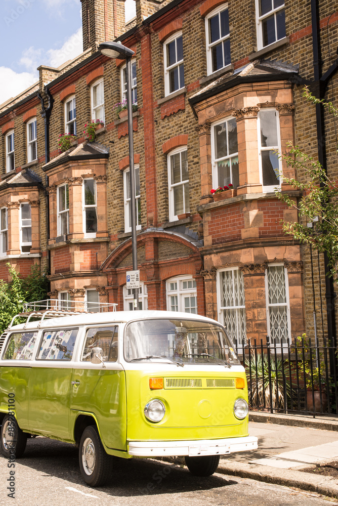Obraz premium Old vintage green van parked in a street with victorian houses