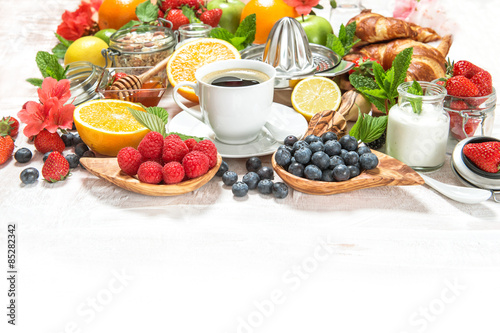 Breakfast with coffee, croissants, muesli, berries, fruits, yogu