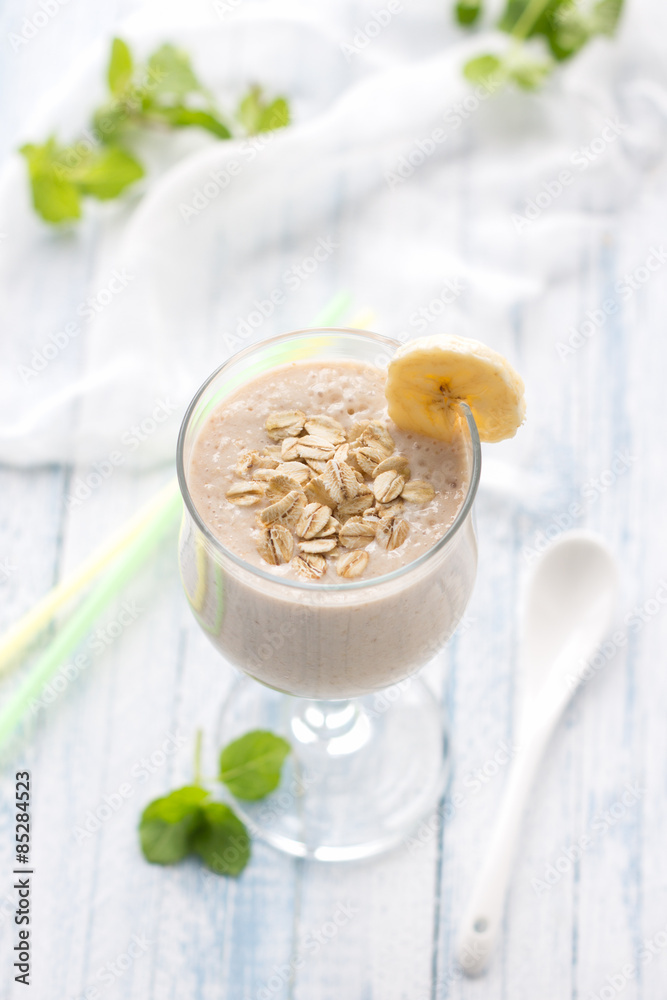 Healthy banana smoothies with oatmeal in a glass on a blue background Healthy banana smoothies with oatmeal in a glass on a blue background