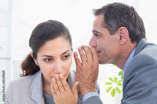 Businessman whispering something to his colleague