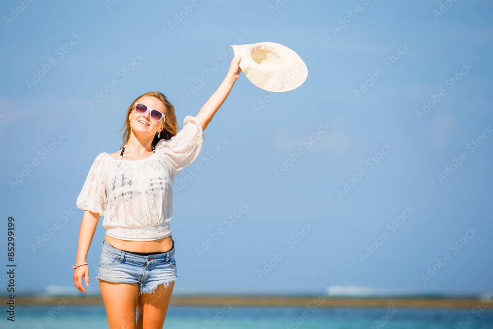 Young skinny caucasian girl at the beach waving with white hat