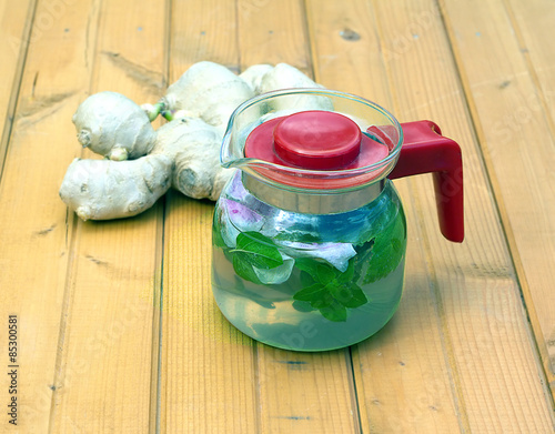 Spa tea with briar, mint and ginder in glass kettle on brown table photo