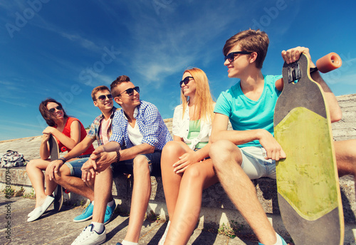 group of smiling friends sitting on city street © Syda Productions