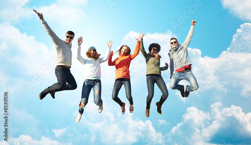 smiling friends in sunglasses jumping high